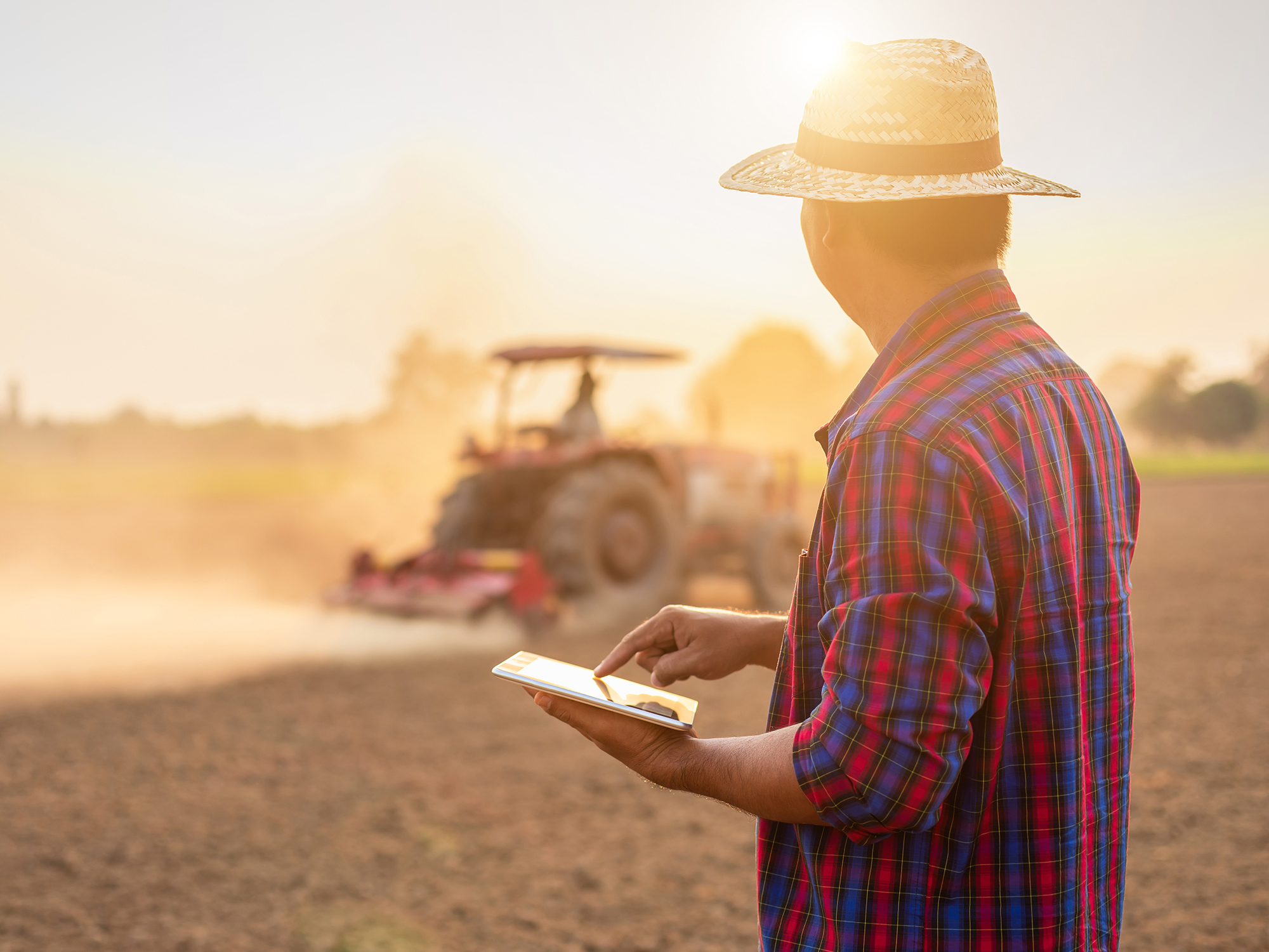 Asian young farmer working and holding tablet in the empty land.